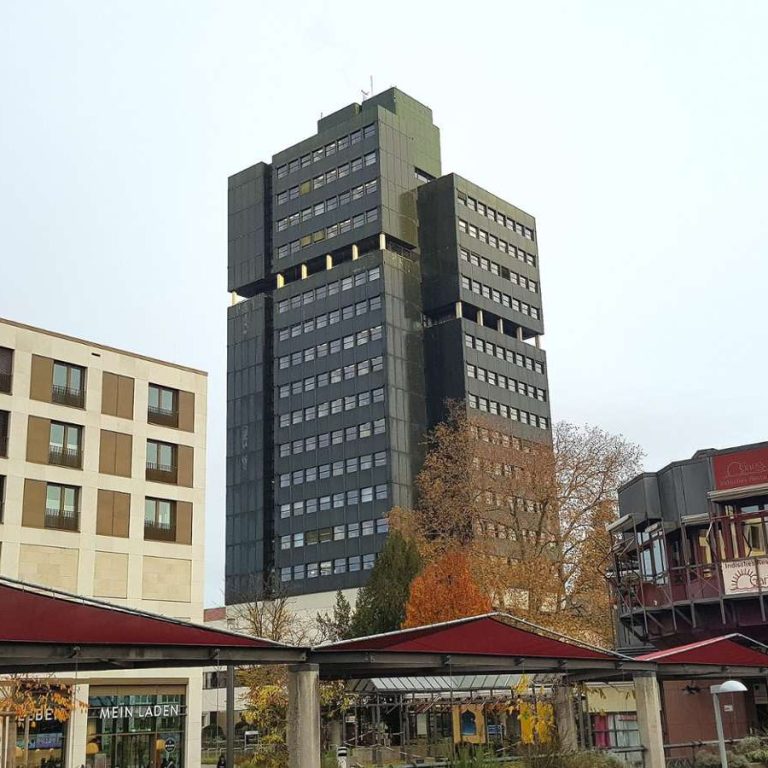 Hochhaus mit moderner Architektur, umgeben von niedrigen Gebäuden und Bäumen in Lörrach 